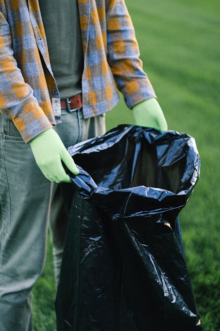 A crumpled plastic bag with a predominantly blue and white design lies discarded on the edge of a concrete sidewalk, partially pressed against the curb. The bag appears to be made of thin, flexible pl
