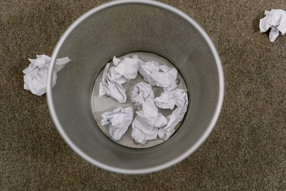 Three large blue plastic rubbish bags are placed on the pavement next to the rear of a white delivery van. The bags appear to be filled with waste materials, showing a somewhat wrinkled and bulky text